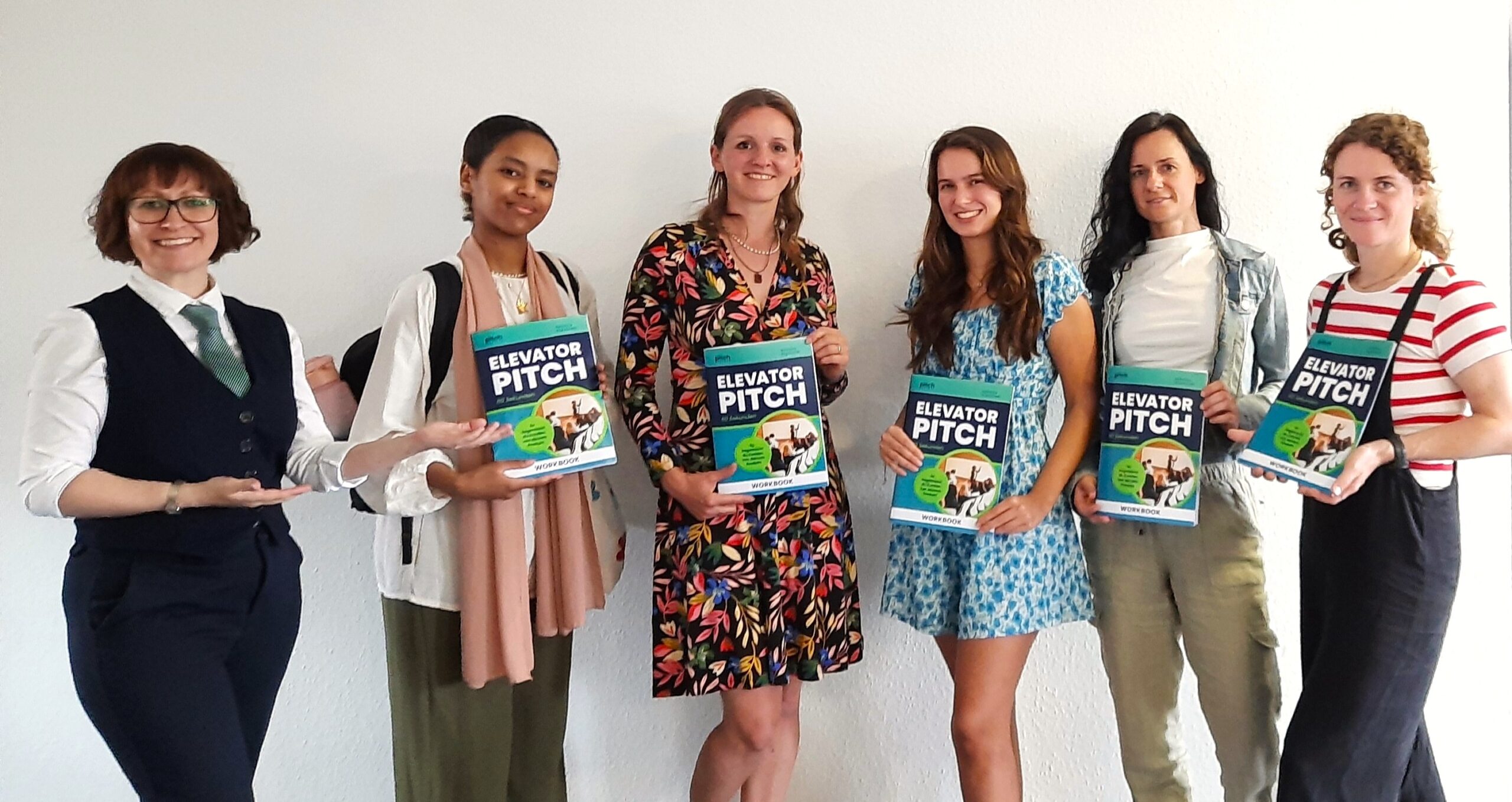5 Teilnehmerinnen des EXIST Women Programms aus Koblenz stehen neben der Trainerin und halten das ELEVATOR PITCH Workbook in den Händen.