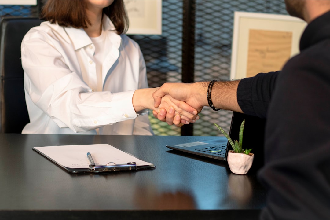 Photo by Mina Rad a man and a woman shaking hands in front of a laptop